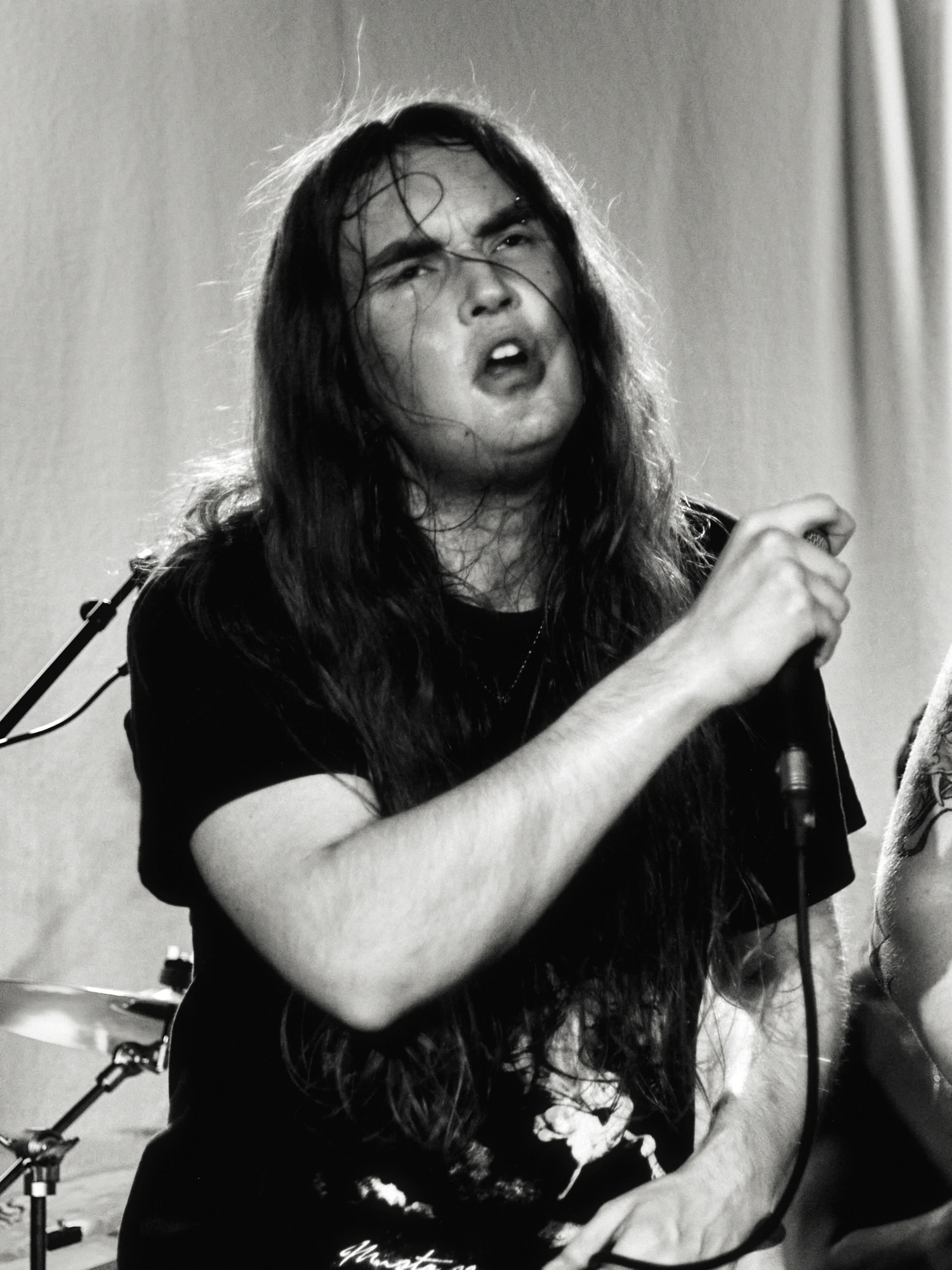 A black and white gig photo of a band performing live on stage. The musicians are captured in action with stage lighting illuminating them.