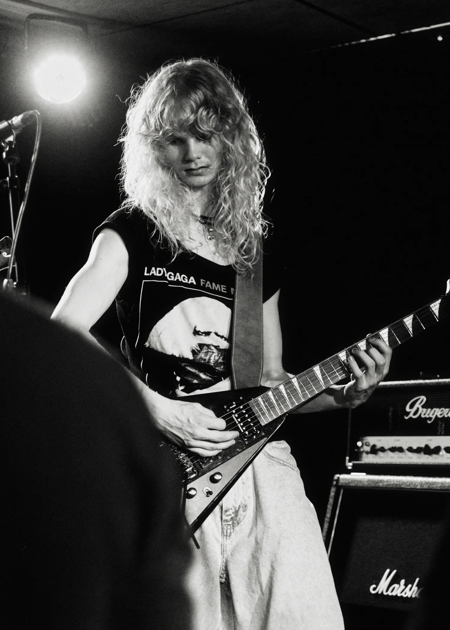 A black and white gig photo of a band performing live on stage. The musicians are captured in action with stage lighting illuminating them.