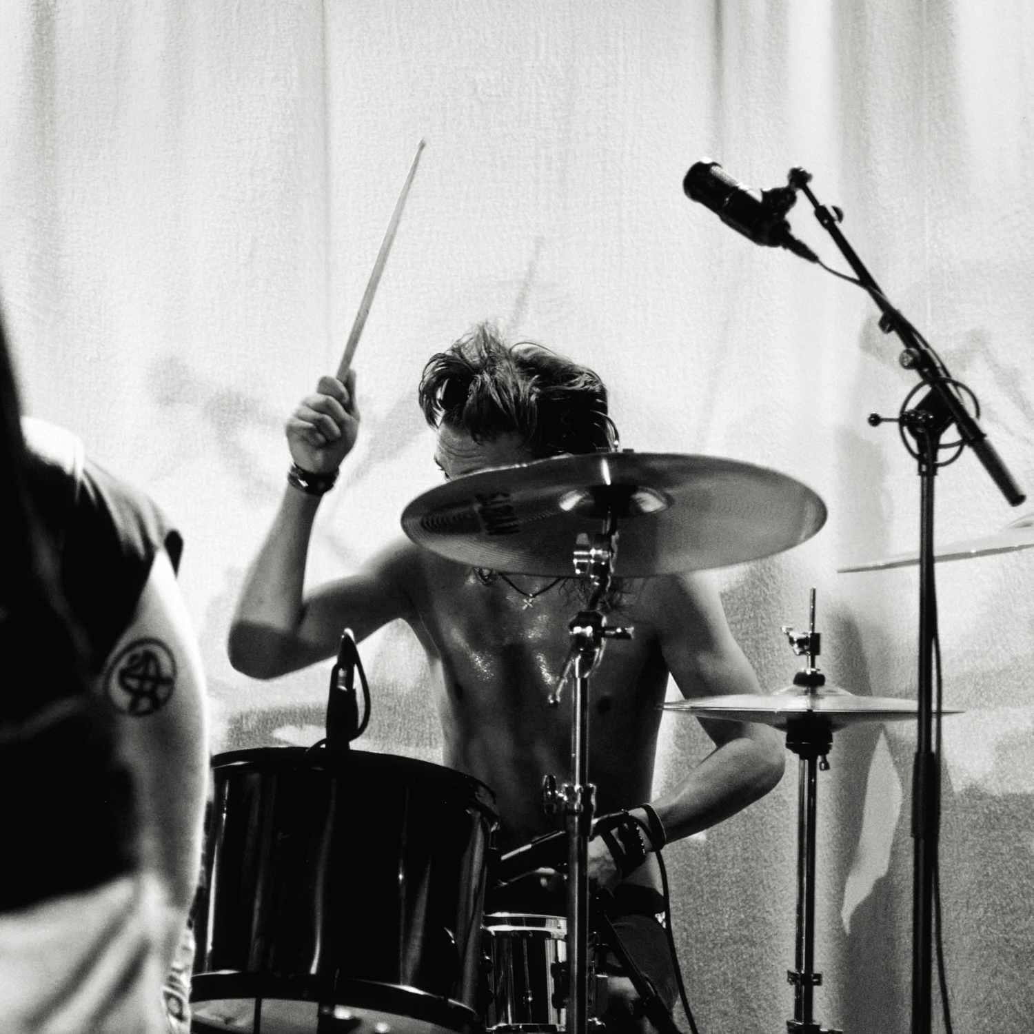 A black and white gig photo of a band performing live on stage. The musicians are captured in action with stage lighting illuminating them.